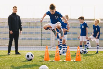 soccer school training unit football boys team practice session youth coach player jumping over cones grass field 187226047